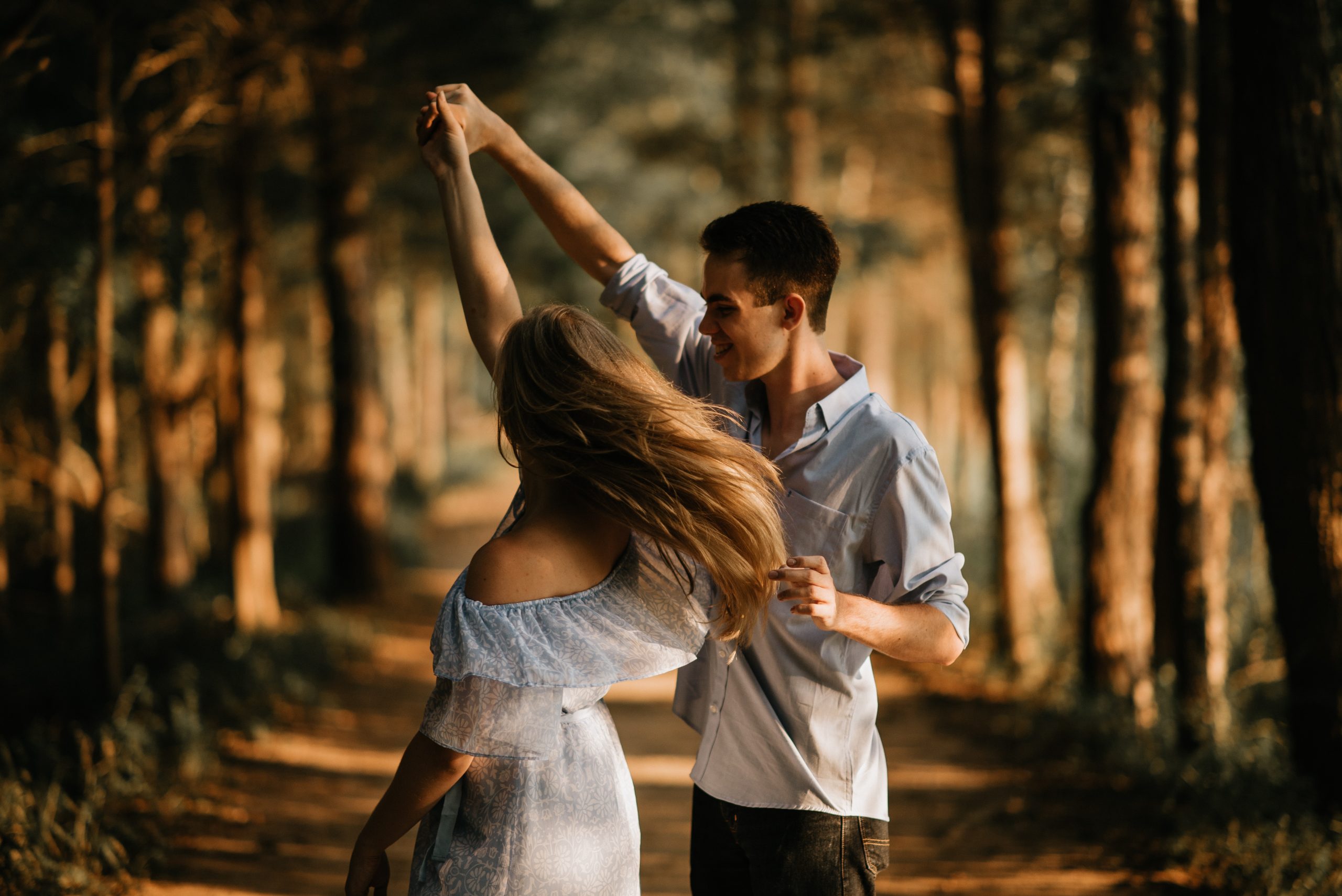 Couple smiling and dancing in a forest, representing couples counseling