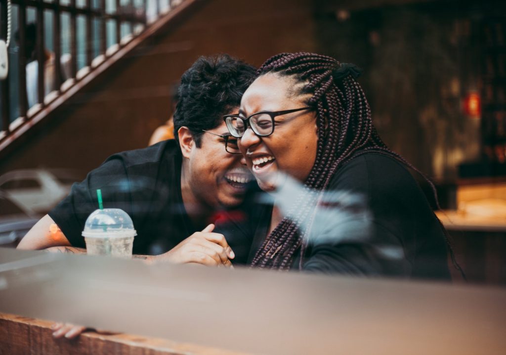 A couple sitting at a coffee shop together and laughing