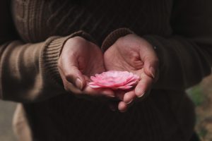 Person holding a flower in their hands to represent self love