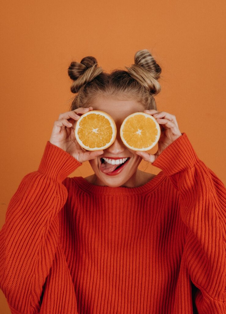 woman holding two slices of orange