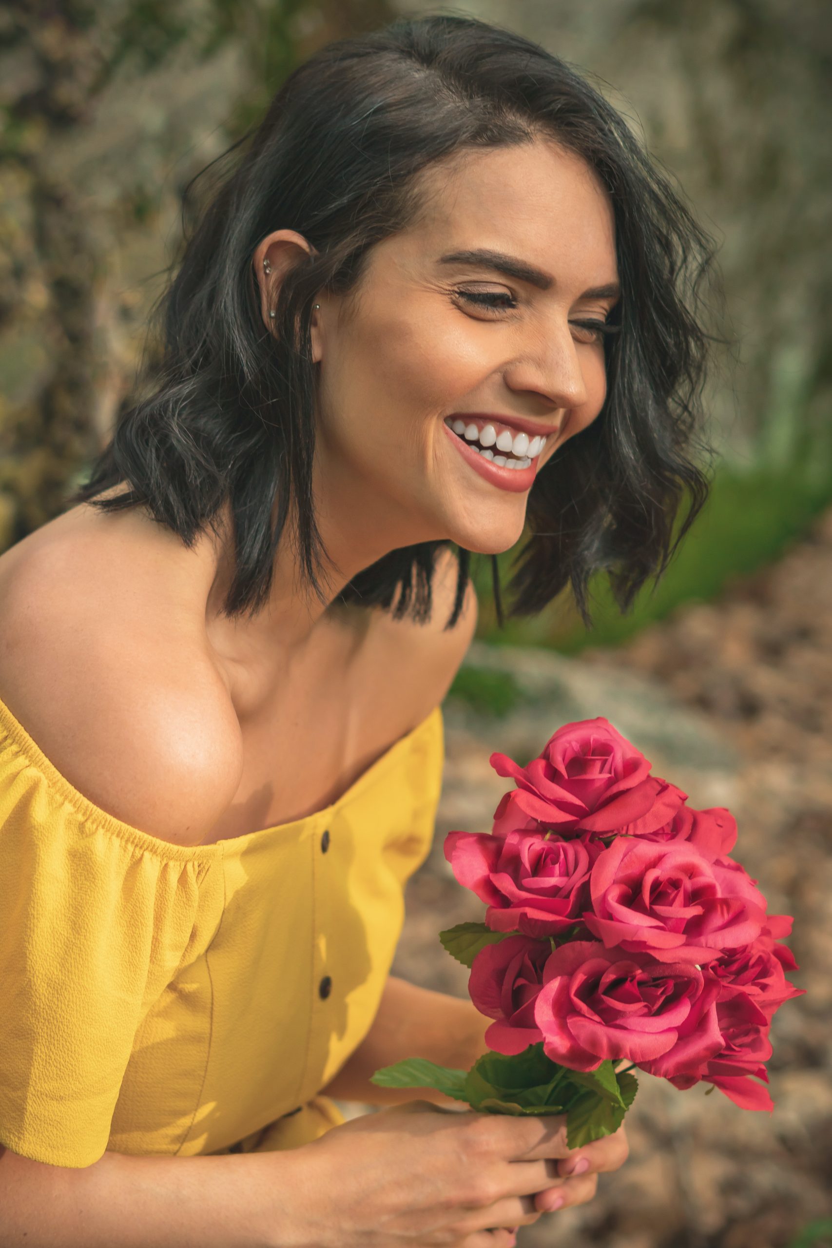 Woman in yellow dress smiling while holding roses. Representing support groups for women.